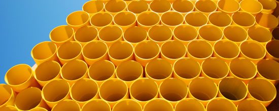 stack of yellow plastic pipes and blue sky